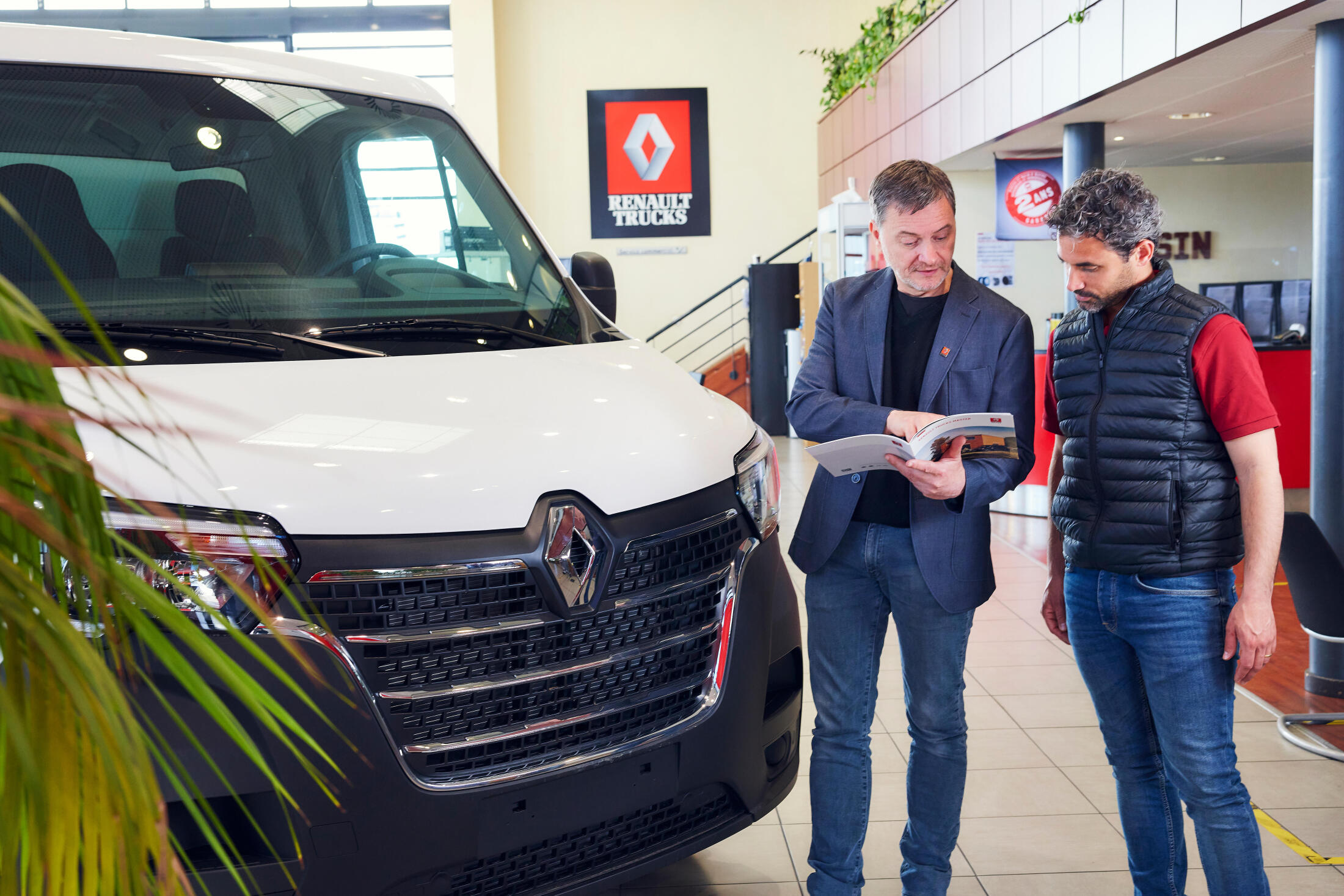 A salesman and a customer discussing in front of a Renault Truck Master